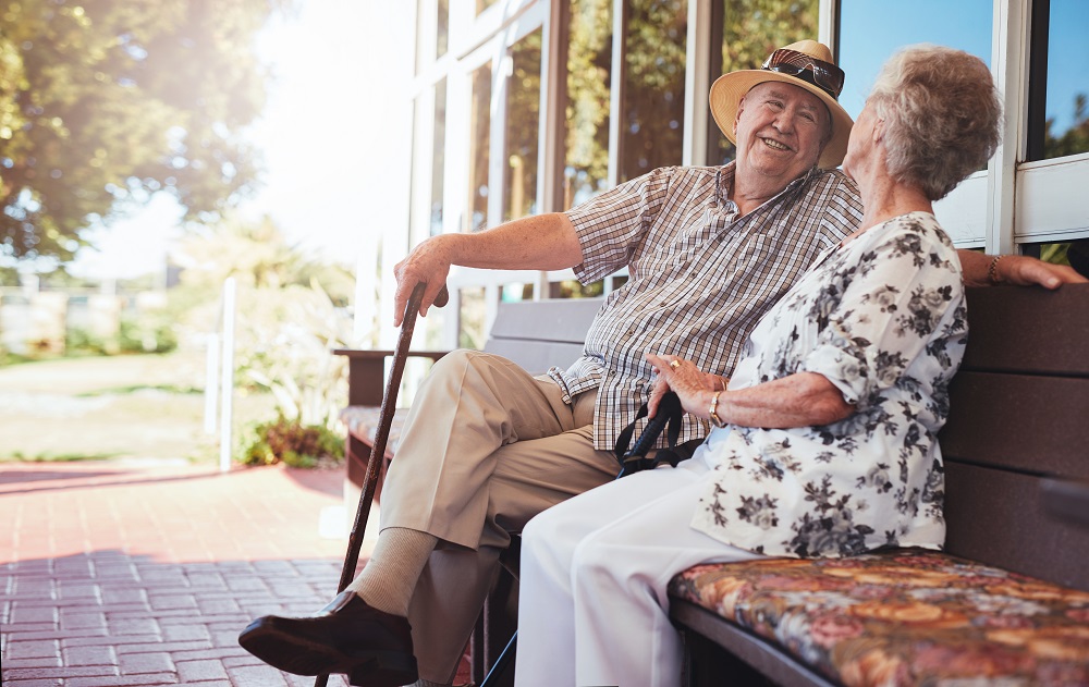 Happy senior couple relaxing on bench outside their house